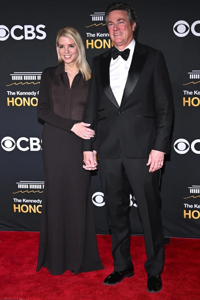 A formally dressed couple poses together on the red carpet at the Kennedy Center Honors, with a black event backdrop featuring Kennedy Center and CBS logos.