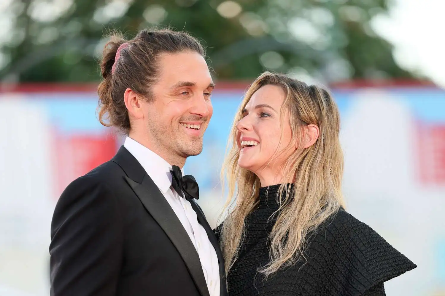 Rebecca Ferguson and her husband Rory St. Clair Gainer smiling at each other on the red carpet at the 2025 Venice International Film Festival.