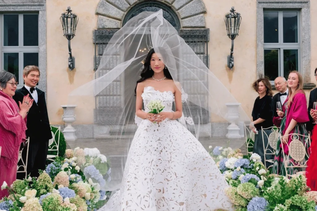 Becca Bloom walking down the aisle in a custom Oscar de la Renta wedding gown at Lake Como