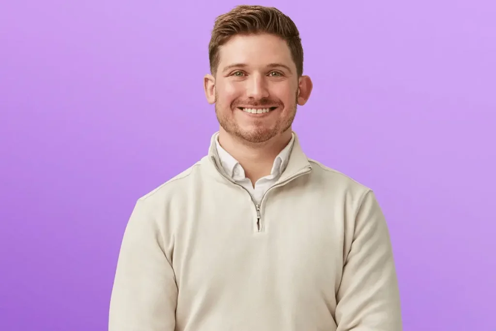 Chris Fusco smiling in a beige quarter-zip sweater against a purple background for Love Is Blind Season 10.