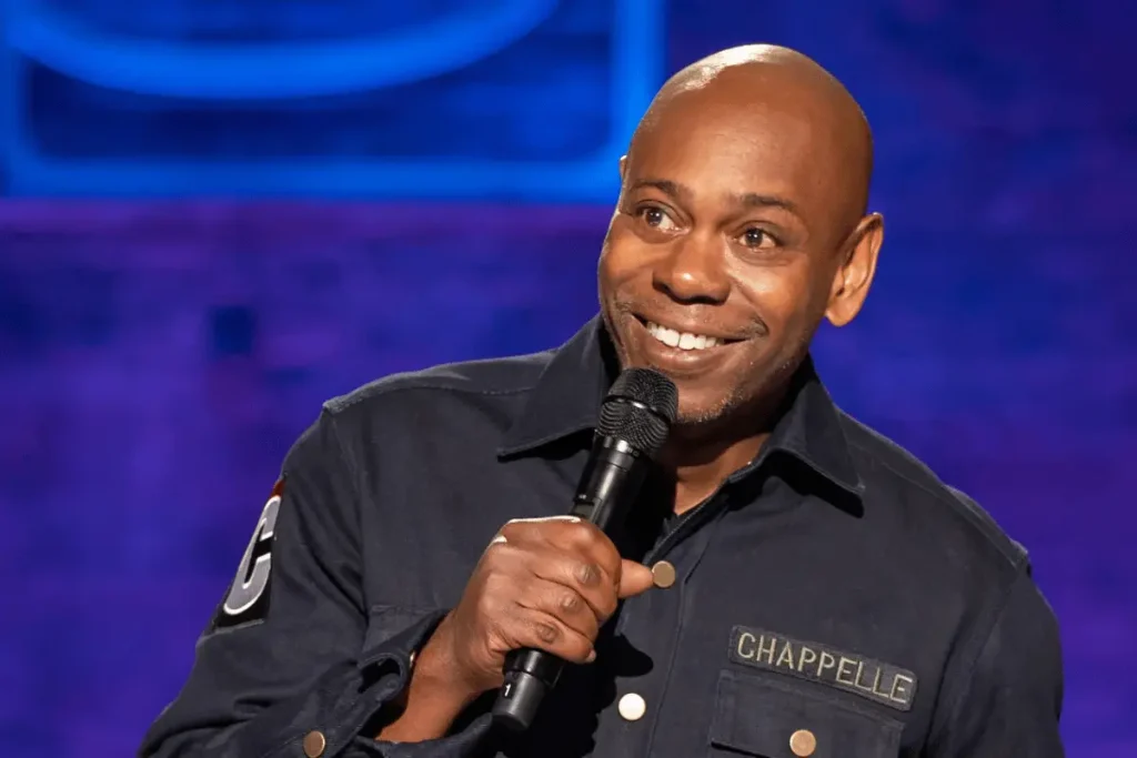 Dave Chappelle performing stand-up comedy on stage with a microphone