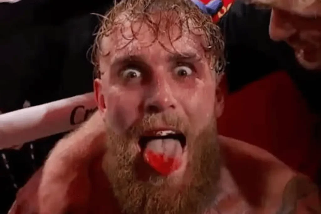 Jake Paul reacting intensely inside the boxing ring with his mouth open and red mouthpiece visible.
