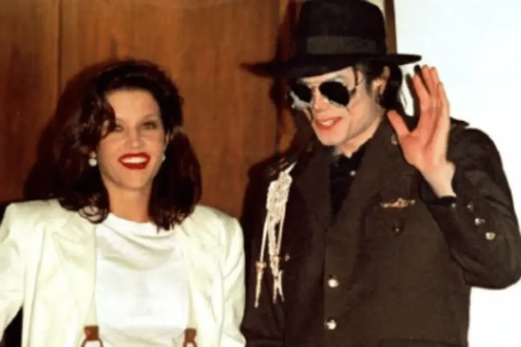 Lisa Marie Presley smiling next to Michael Jackson, who is wearing a black hat, sunglasses, and a military-style jacket while waving.