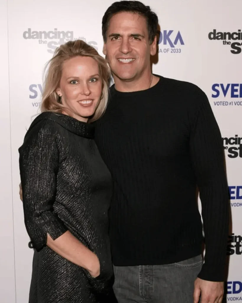 Tiffany Stewart in a black sparkly dress and Mark Cuban in a black sweater posing together at an evening event.