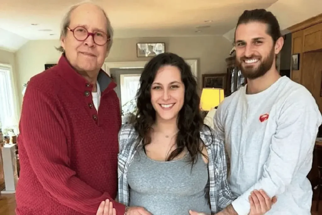 Emily Chase poses with her father, Chevy Chase, and partner Alex Baglieri following the announcement of her first child.